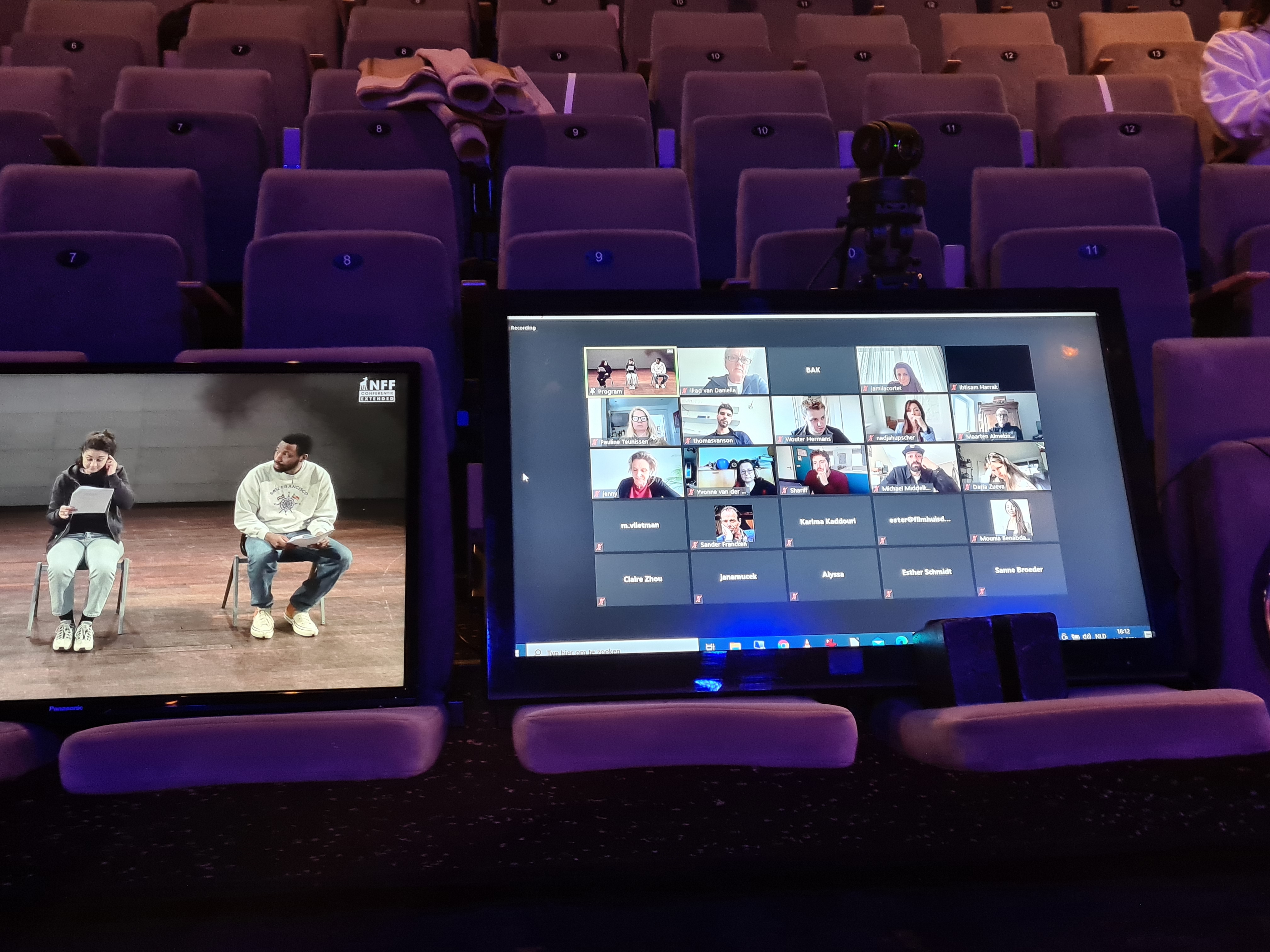 twee laptops met Zoom open staan op de stoelen op de tribune van een theater